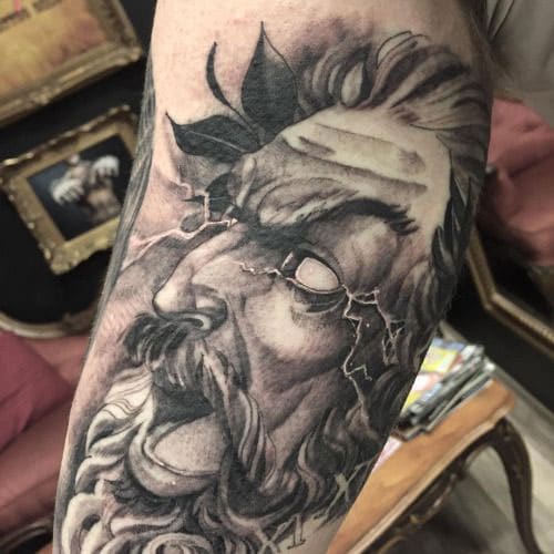 Stylized tattoo of Zeus with his mouth open and lightning coming out of his eyes.