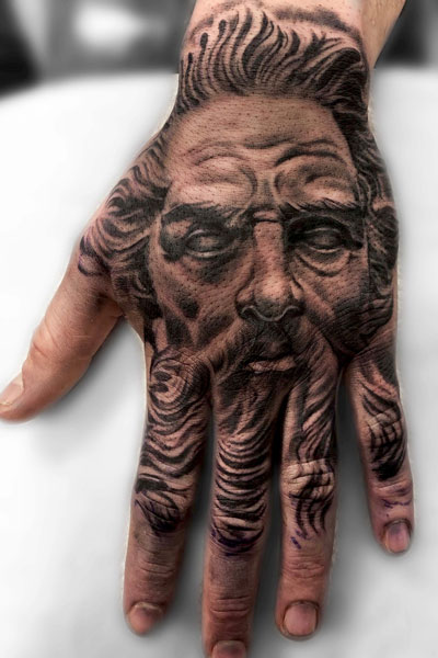 Full hand and finger tattoo of Zeus's face.