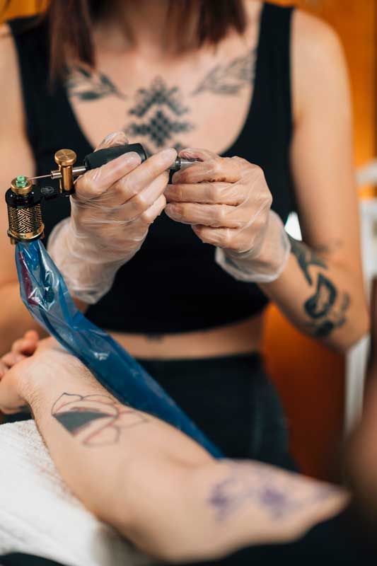 female tattoo artist prepares tattoo machine